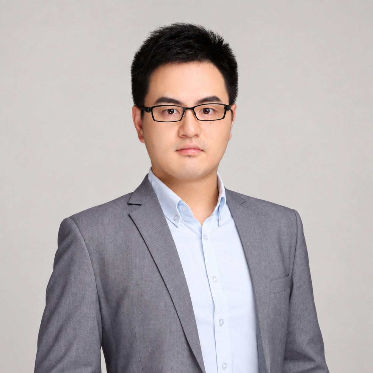 Pimi Pan wearing glasses and a gray suit against a light warm gray background